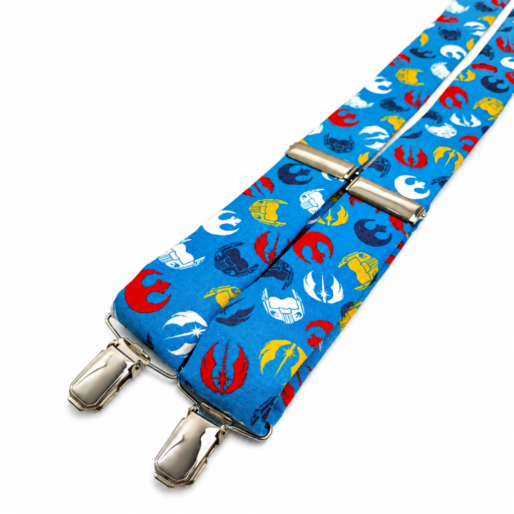 Tirantes Galaxia Wars artesanales para hombre fabricados a mano en España. Tirantes azul galáctico con símbolos inspirados en Star Wars en colores rojo, amarillo, blanco y azul marino. Complemento original para bodas, novios, invitados, comuniones, bautizos, eventos temáticos, convenciones y celebraciones especiales. Tirantes de algodón premium con forma en Y, pinzas metálicas resistentes y longitud ajustable. Regalo perfecto para amantes de la ciencia ficción, cultura geek, cine fantástico y universo galáctico. ENGLISH: Galaxy Wars suspenders handmade in Spain for men. Blue galaxy suspenders featuring iconic space inspired symbols in red, yellow, white and navy blue colors. Premium cotton suspenders with Y-back design, adjustable length and strong metal clips. Perfect for weddings, grooms, wedding guests, parties, themed events, comic conventions and science fiction fans. Stylish, elegant and original men's accessory inspired by the galaxy universe and space adventures. FRANÇAIS : Bretelles Galaxia Wars fabriquées artisanalement en Espagne pour homme. Bretelles bleu galaxie avec symboles inspirés de l'univers spatial en rouge, jaune, blanc et bleu marine. Bretelles en coton premium avec forme en Y, longueur réglable et attaches métalliques robustes. Accessoire élégant pour mariages, mariés, invités, baptêmes, communions, fêtes et événements à thème. Cadeau idéal pour les amateurs de science-fiction, cinéma fantastique et univers galactique. ITALIANO: Bretelle Galaxia Wars artigianali realizzate a mano in Spagna. Bretelle blu galassia con simboli ispirati all'universo spaziale nei colori rosso, giallo, bianco e blu navy. Bretelle da uomo in cotone premium con forma a Y, lunghezza regolabile e clip metalliche resistenti. Perfette per matrimoni, sposi, invitati, battesimi, comunioni, eventi speciali e convention dedicate alla fantascienza. Idea regalo originale per appassionati di galassie, cinema fantasy e cultura geek.