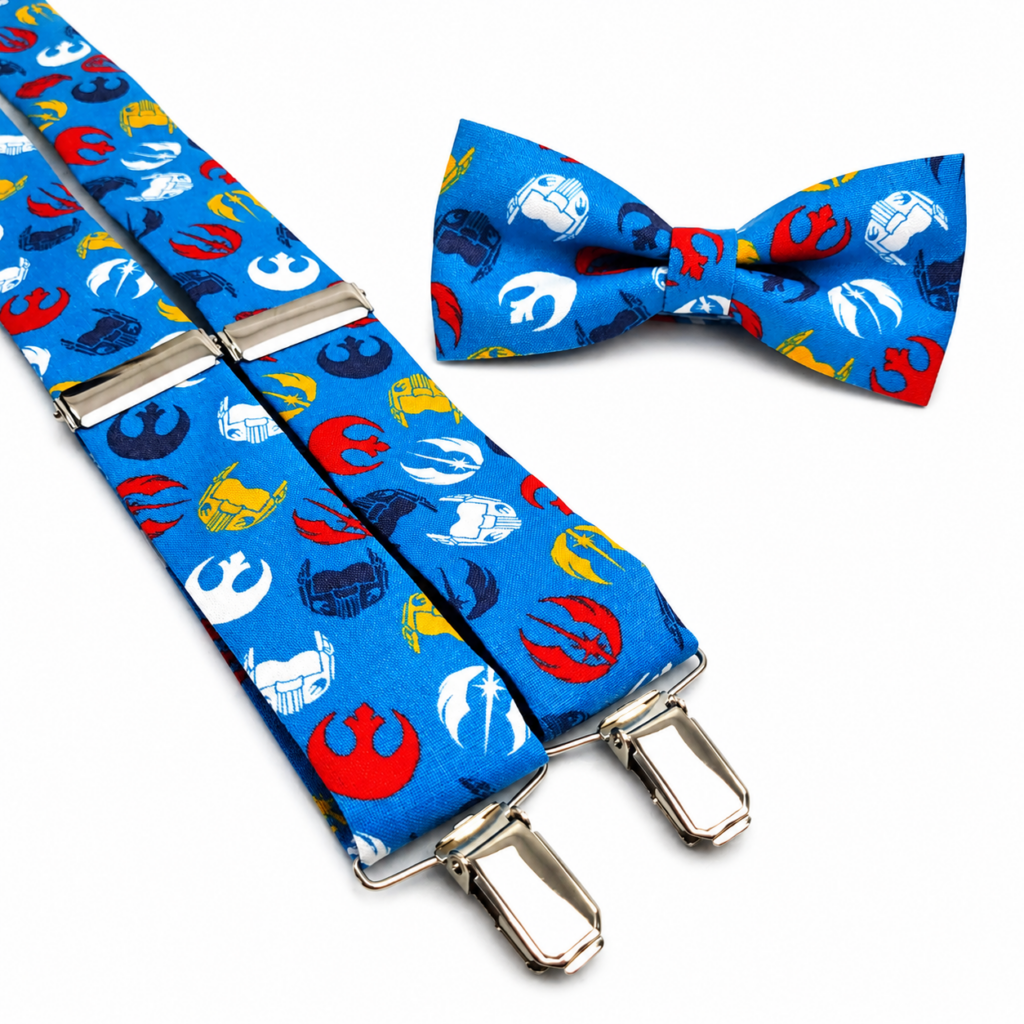 Pajarita y tirantes Galaxia Wars artesanales para hombre hechos a mano en España. Conjunto elegante con fondo azul galaxia y símbolos espaciales en colores rojo, blanco, amarillo y azul marino. Complemento exclusivo fabricado en algodón premium ideal para bodas, novios, invitados, comuniones, bautizos, eventos especiales, celebraciones, fiestas temáticas, ferias del cómic, convenciones de ciencia ficción y regalos originales para hombre. Pajarita artesanal ajustable y tirantes elásticos de alta calidad fabricados en Murcia por Pajaritas con Jota. ENGLISH: Galaxy Wars bow tie and suspenders handmade in Spain. Elegant men's accessory set featuring a bright blue galaxy background with space-inspired symbols in red, white, yellow and navy blue. Crafted from premium cotton and designed for weddings, grooms, wedding guests, christenings, communions, formal events, geek conventions, science fiction fans, comic events and unique gifts for men. Handmade artisan bow tie and suspenders created with high quality materials and professional finishes. FRANÇAIS : Noeud papillon et bretelles Galaxia Wars fabriqués à la main en Espagne. Ensemble élégant pour homme avec fond bleu galaxie et symboles spatiaux rouges, blancs, jaunes et bleu marine. Confection artisanale en coton premium idéale pour mariages, mariés, invités, baptêmes, communions, événements spéciaux, fêtes, conventions geek, passionnés de science-fiction et cadeaux originaux pour homme. Accessoire exclusif réalisé dans un atelier artisanal avec finitions de haute qualité. ITALIANO: Papillon e bretelle Galaxia Wars fatti a mano in Spagna. Elegante set da uomo con sfondo blu galassia e simboli spaziali nei colori rosso, bianco, giallo e blu navy. Realizzato in cotone premium di alta qualità, perfetto per matrimoni, sposi, invitati, comunioni, battesimi, eventi speciali, convention geek, appassionati di fantascienza e idee regalo originali per uomo. Papillon artigianale e bretelle regolabili realizzati con cura nel laboratorio artigianale Pajaritas con Jota.