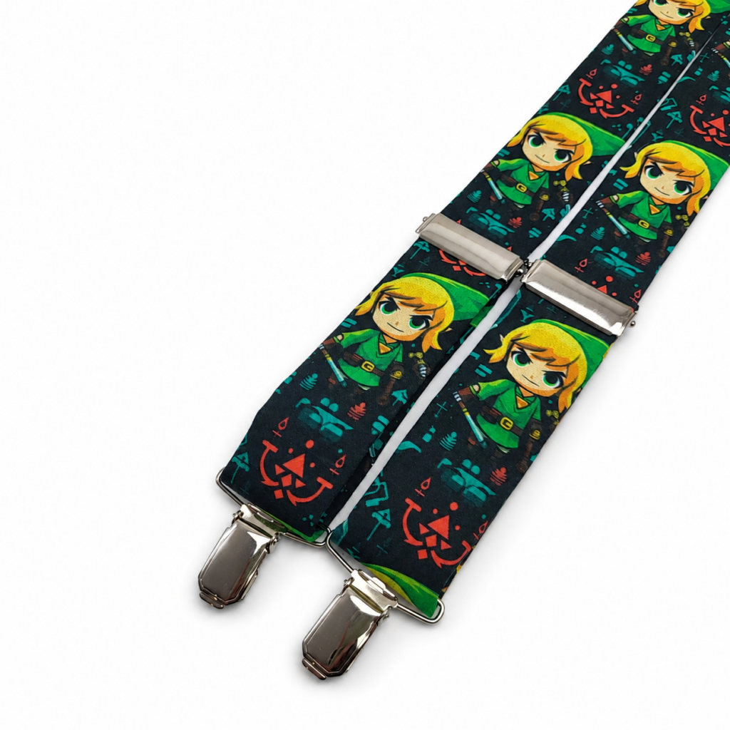 Tirantes Zelda artesanales para hombre confeccionados en algodón y fabricados completamente a mano en nuestro taller de Pajaritas con Jota en Murcia, España. Tirantes originales con fondo negro oscuro y estampado de personajes de cabello rubio vestidos principalmente en verde, acompañados de símbolos y pequeños detalles en verde esmeralda, azul turquesa, rojo, amarillo, marrón y dorado. Incorporan reguladores metálicos y pinzas plateadas ajustables. Tirantes Zelda para bodas, novios, invitados, comuniones, bautizos, fiestas, ceremonias y eventos especiales. Complemento inspirado en videojuegos y fantasía que combina especialmente bien con camisa blanca y traje azul marino, negro, gris, verde botella o beige. Tirantes de algodón hechos a mano, ideales como regalo original para gamers, aficionados a Zelda y hombres que buscan complementos diferentes. English SEO ALT text — more than 100 words Zelda suspenders for men handmade from cotton in our Pajaritas con Jota workshop in Murcia, Spain. Original dark suspenders featuring blonde fantasy characters dressed mainly in green, surrounded by decorative symbols and small details in emerald green, turquoise blue, red, yellow, brown and gold tones. The suspenders include adjustable silver metal fittings and strong metal clips for a comfortable fit. These Zelda suspenders are perfect for weddings, grooms, wedding guests, communions, baptisms, parties, ceremonies and other special events. They look especially stylish with a white shirt and navy blue, black, grey, bottle green or beige suit. Handmade cotton suspenders made in Spain and an original gift idea for gamers, Zelda fans, fantasy lovers and men looking for unusual wedding accessories. Texte ALT SEO en français — plus de 100 mots Bretelles Zelda artisanales pour homme fabriquées en coton et confectionnées entièrement à la main dans notre atelier Pajaritas con Jota à Murcie, en Espagne. Bretelles originales sur fond noir foncé avec des personnages blonds habillés principalement en vert, accompagnés de symboles et petits motifs en vert émeraude, bleu turquoise, rouge, jaune, marron et doré. Elles disposent de réglages métalliques et de pinces argentées permettant d’adapter facilement leur longueur. Ces bretelles Zelda sont parfaites pour mariage, marié, invité, communion, baptême, fête, cérémonie et événement spécial. Elles se combinent particulièrement bien avec une chemise blanche et un costume bleu marine, noir, gris, vert bouteille ou beige. Bretelles en coton faites main en Espagne, idéales comme cadeau original pour gamers et amateurs de Zelda. Testo ALT SEO in italiano — più di 100 parole Bretelle Zelda artigianali da uomo realizzate in cotone e confezionate completamente a mano nel nostro laboratorio Pajaritas con Jota a Murcia, in Spagna. Bretelle originali con fondo nero scuro e stampa caratterizzata da personaggi biondi vestiti principalmente di verde, accompagnati da simboli e piccoli dettagli nei colori verde smeraldo, blu turchese, rosso, giallo, marrone e dorato. Sono dotate di regolatori metallici e robuste clip argentate regolabili. Le Bretelle Zelda sono perfette per matrimonio, sposo, invitati, comunione, battesimo, festa, cerimonia ed eventi speciali. Si abbinano molto bene a una camicia bianca e a un abito blu navy, nero, grigio, verde bottiglia o beige. Bretelle di cotone fatte a mano in Spagna, ideali come regalo originale per gamer e appassionati di Zelda.